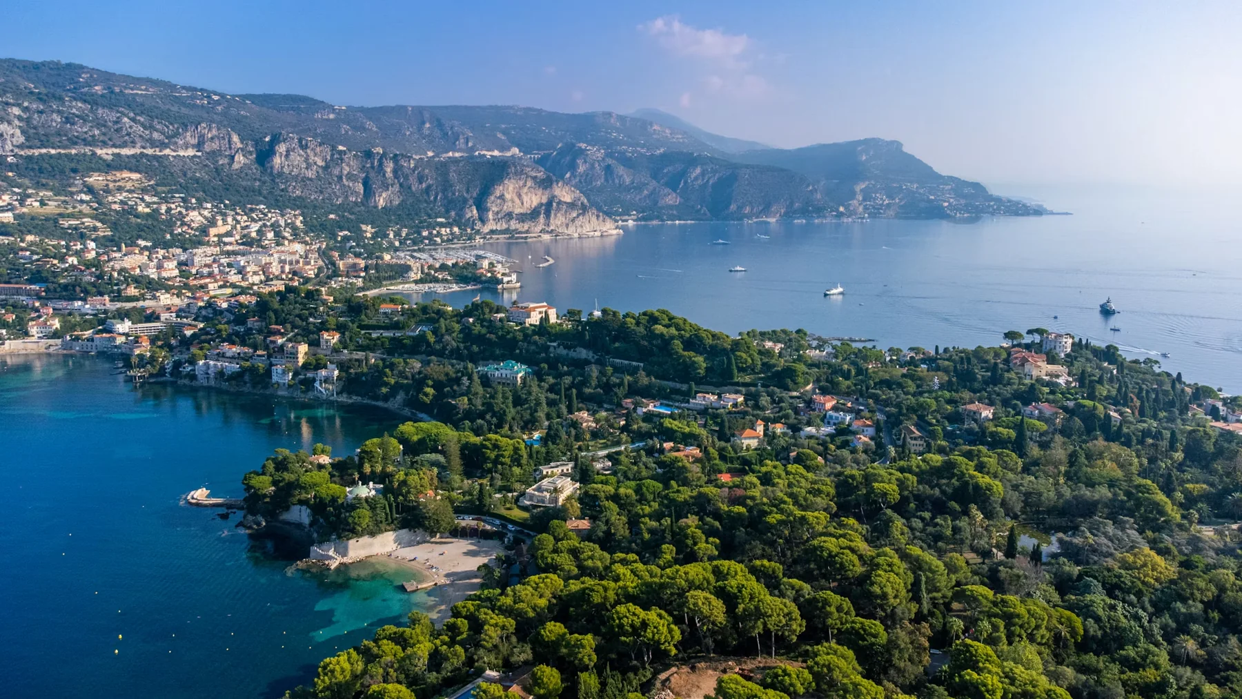 Aerial view of Saint-Jean-Cap-Ferrat, its pine forests and turquoise bays, with Beaulieu and the cliffs beyond