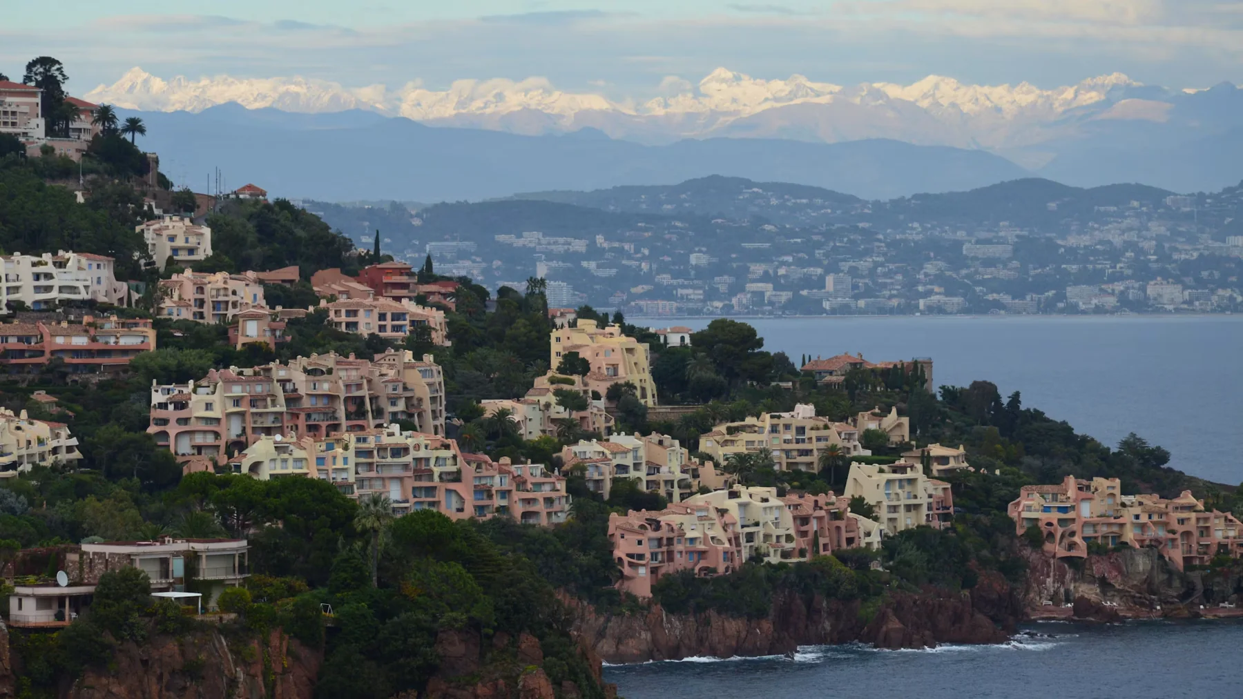Villas on the red rocks of the Esterel coast with the snowy Alps beyond