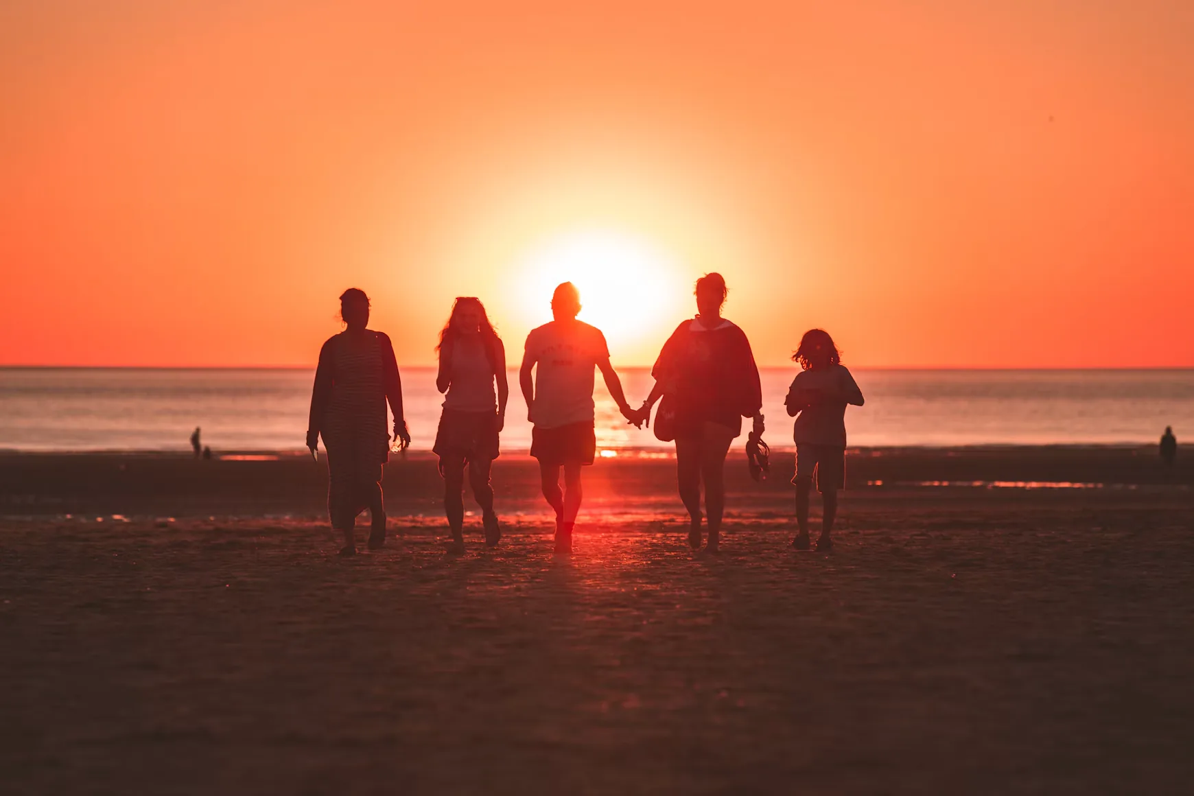 A family walking hand in hand into the sunset
