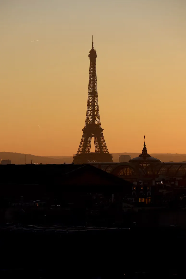 The Eiffel Tower silhouetted against an orange sky