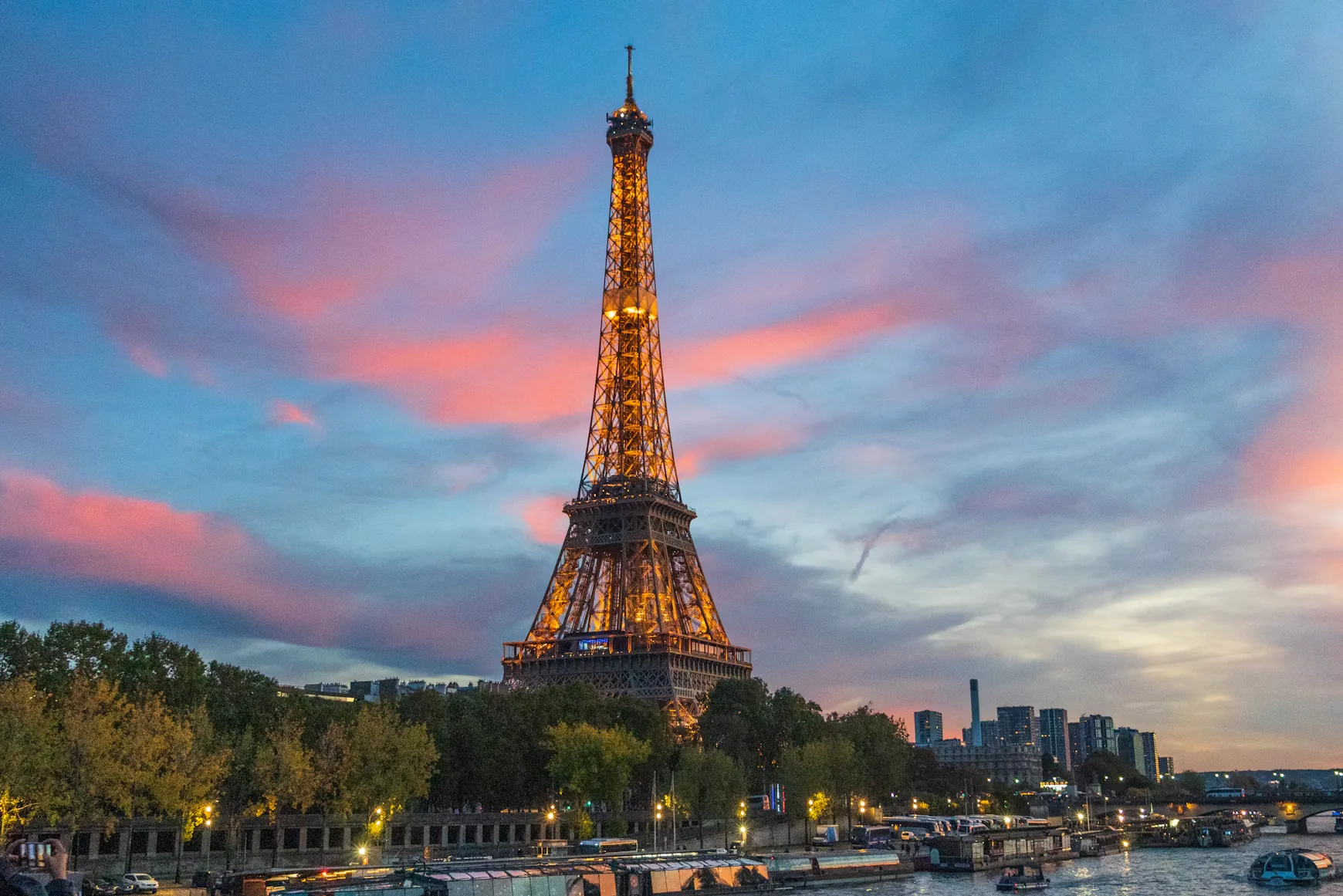 The Eiffel Tower lit up at dusk above the Seine
