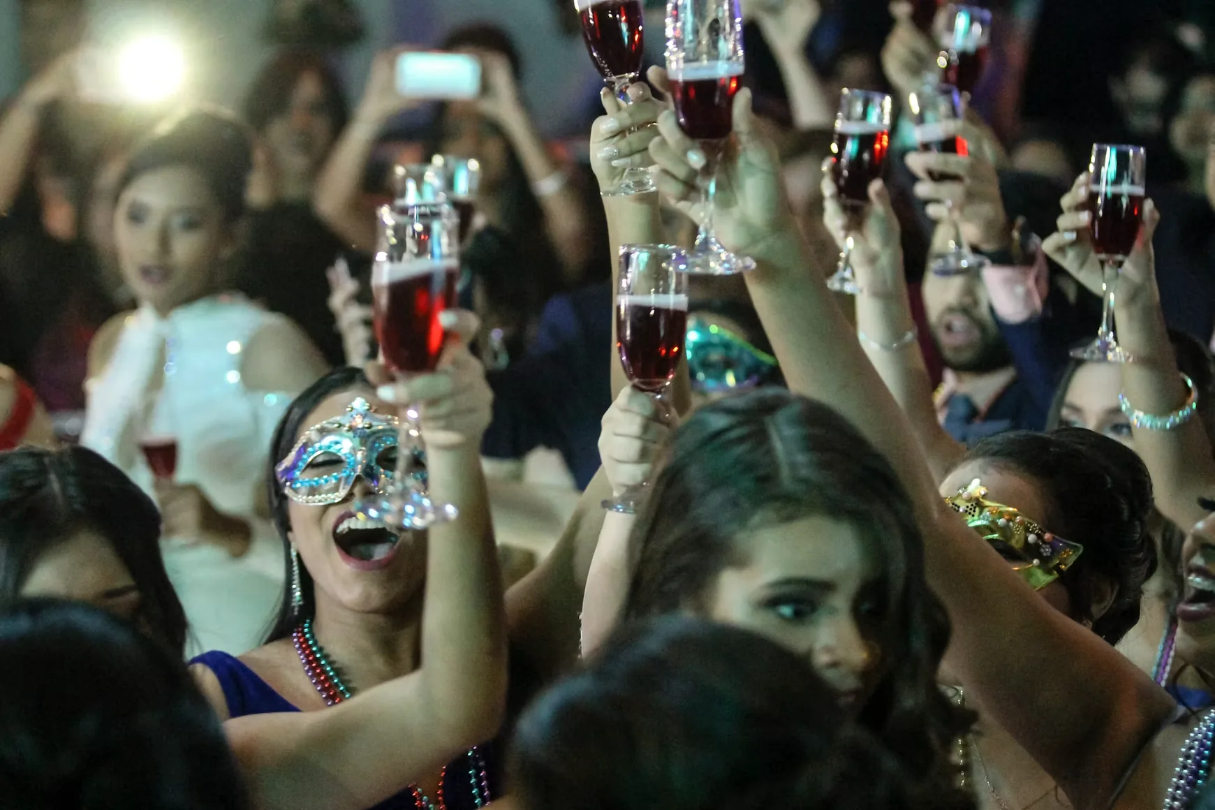 Guests raising glasses at a masked party